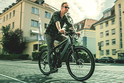 Zu sehen ist ein Mann auf einem Winora Fahrrad, der durch die Innenstadt fährt.