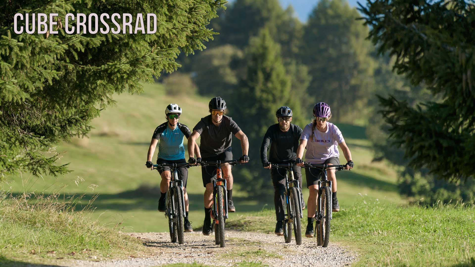 Zu sehen ist eine Gruppe von Radfahrern, welche über einen Waldweg fahren. Das Bild ist beschriftet mit dem Titel Cube Crossrad.