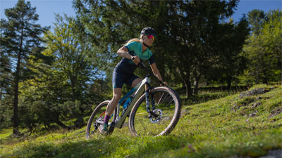 Zu sehen ist eine Fahrradfahrerin, auf ihrem Mountainbike. Sie fährt durch steiles Gebiet.