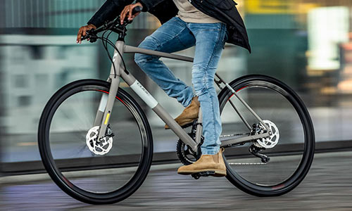 Ein Radfahrer fährt mit seinem Fitnessrad durch die Stadt, der Radfahrer ist nur teilweise sichtbar.