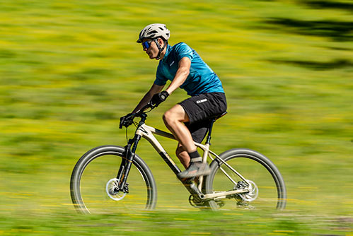 Radfahrer mit blauem T-Shirt und Helm auf einem Cube Reaction Mountainbike-Hardtail.