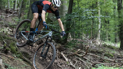 Zu sehen ist eine Fahrradfahrerin, die einen Hang downhill herunter fährt.